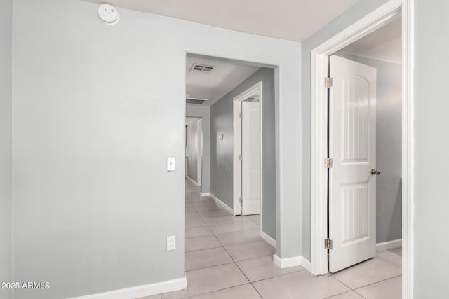 hall with light tile patterned floors, baseboards, and visible vents