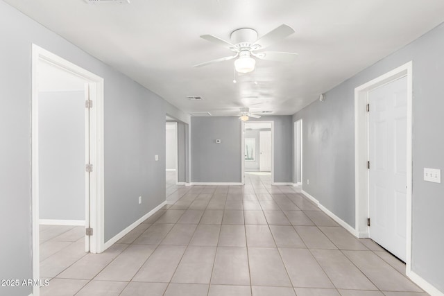 empty room featuring visible vents, light tile patterned flooring, a ceiling fan, and baseboards