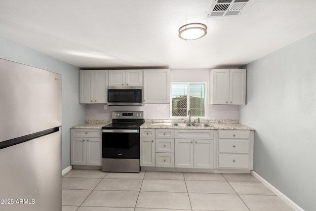 kitchen featuring light tile patterned floors, stainless steel appliances, visible vents, a sink, and baseboards