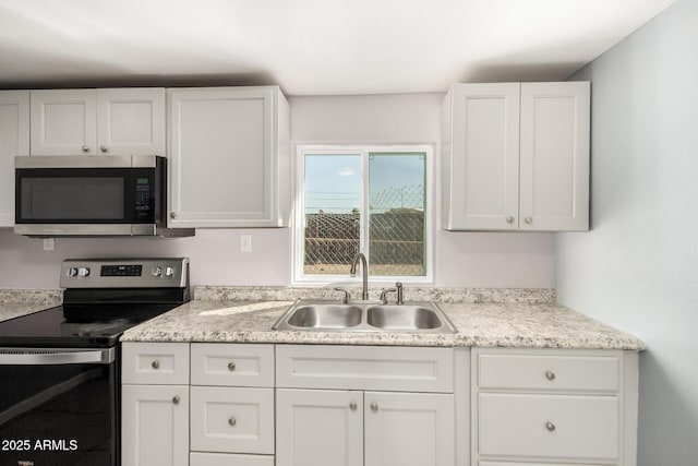 kitchen with white cabinets, stainless steel appliances, a sink, and light countertops