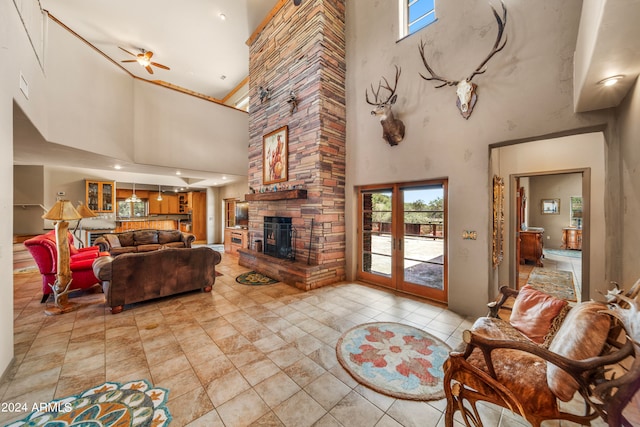 living room with a high ceiling, ceiling fan, and a stone fireplace