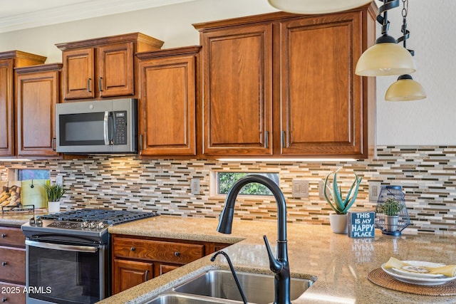 kitchen with sink, crown molding, appliances with stainless steel finishes, light stone countertops, and decorative backsplash