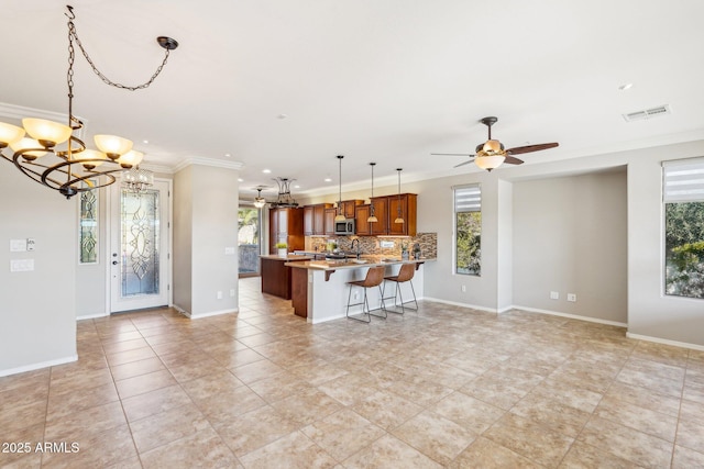 kitchen featuring backsplash, decorative light fixtures, plenty of natural light, and ornamental molding