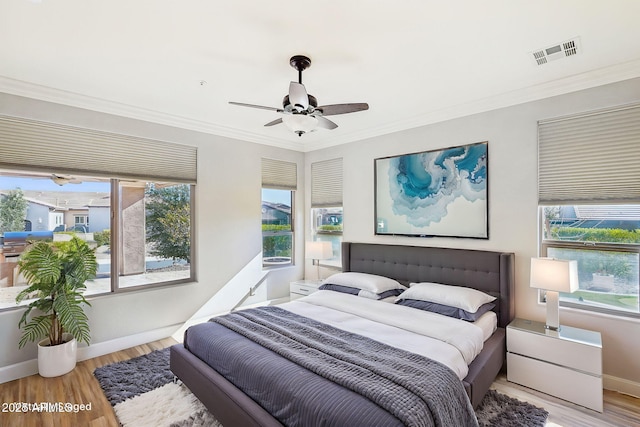 bedroom featuring multiple windows, crown molding, light hardwood / wood-style flooring, and ceiling fan