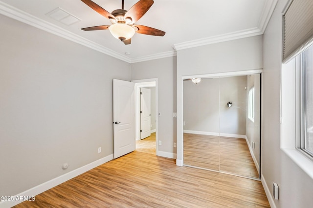 unfurnished bedroom featuring crown molding, light hardwood / wood-style flooring, ceiling fan, and a closet