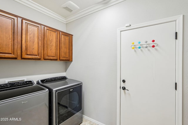 laundry room featuring crown molding, washing machine and dryer, and cabinets