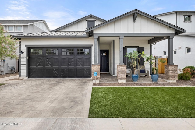 view of front facade with covered porch, a garage, and a front yard