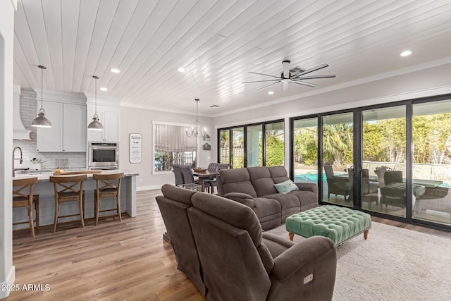 living room with ceiling fan with notable chandelier, ornamental molding, light hardwood / wood-style floors, and wooden ceiling