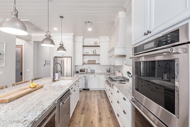 kitchen featuring white cabinetry, appliances with stainless steel finishes, light stone counters, and pendant lighting