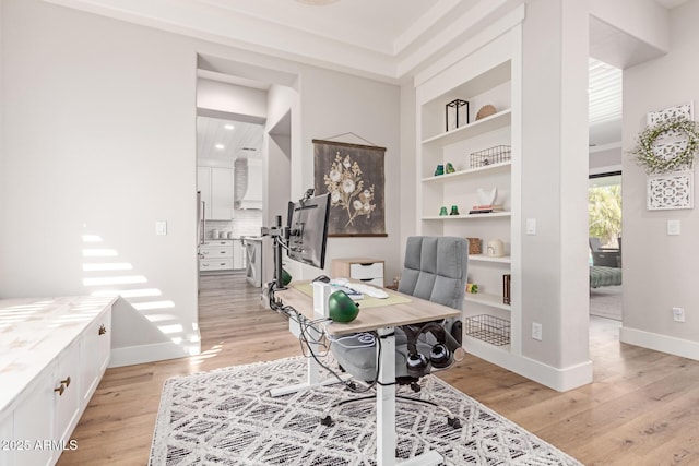 home office with light hardwood / wood-style floors and built in features