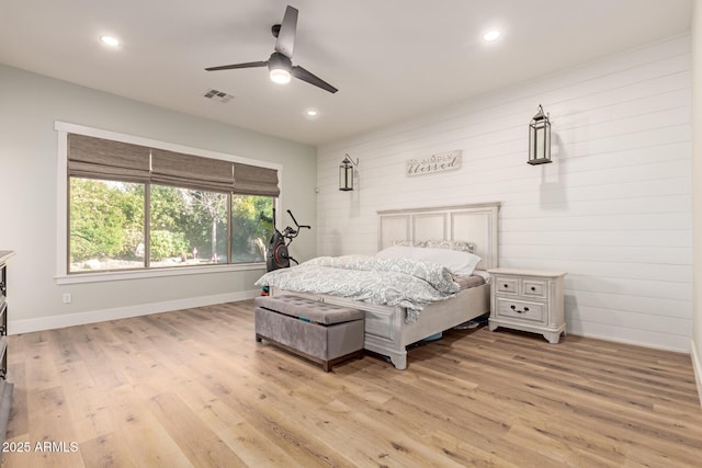 bedroom featuring wooden walls, light hardwood / wood-style floors, and ceiling fan