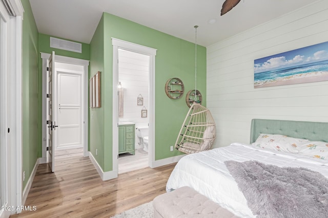 bedroom featuring connected bathroom and light hardwood / wood-style flooring