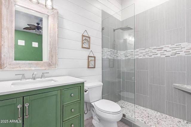 bathroom with ceiling fan, vanity, toilet, and a tile shower