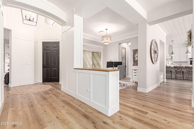 interior space with wood counters, backsplash, decorative light fixtures, and light hardwood / wood-style floors