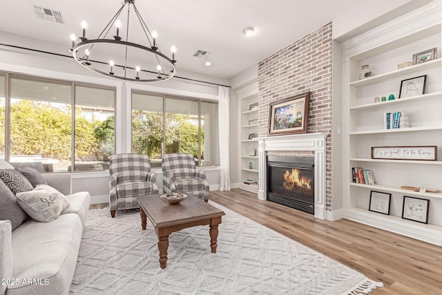 living room with a healthy amount of sunlight, built in features, light hardwood / wood-style floors, and a fireplace