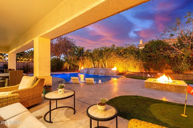 patio terrace at dusk with an outdoor fire pit and a fenced in pool