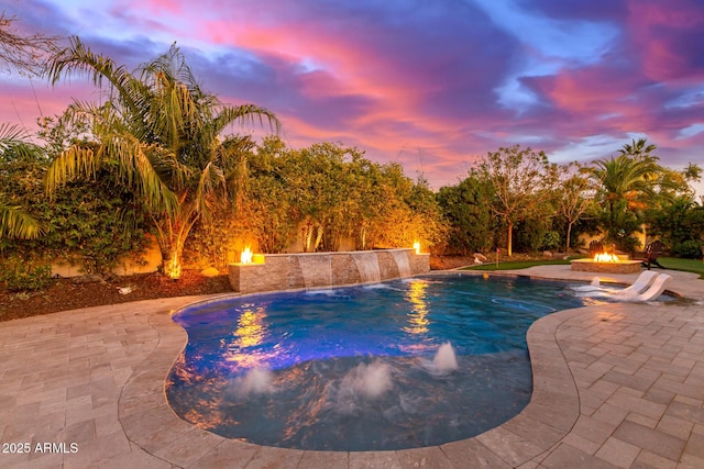 pool at dusk with a patio area and an outdoor fire pit