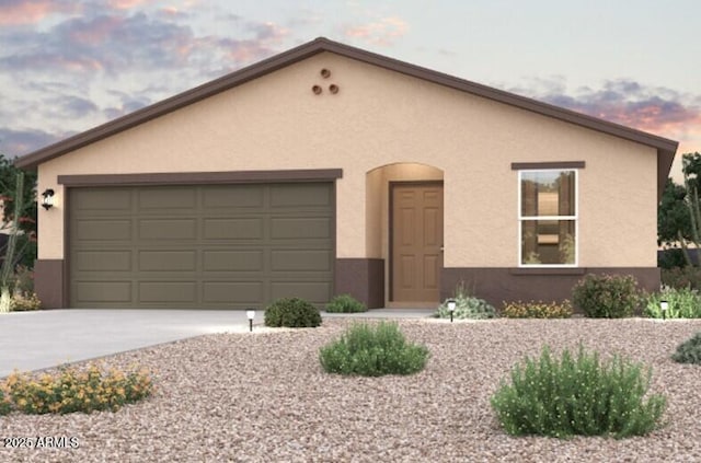 view of front of house with concrete driveway, an attached garage, and stucco siding