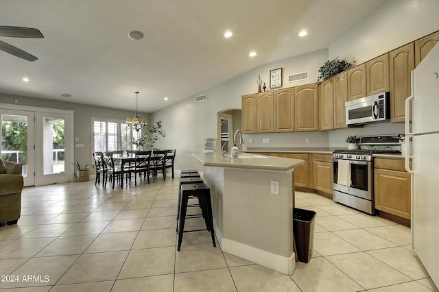 kitchen featuring light tile patterned flooring, appliances with stainless steel finishes, decorative light fixtures, an island with sink, and sink