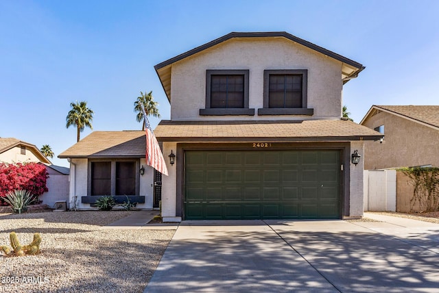 traditional-style house featuring a garage, concrete driveway, and stucco siding