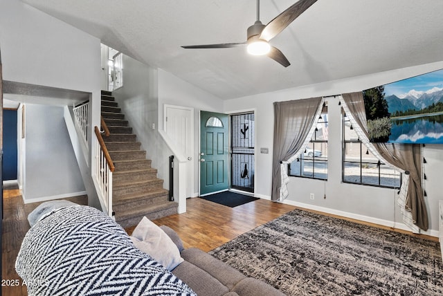 entryway featuring stairway, vaulted ceiling, a textured ceiling, wood finished floors, and baseboards