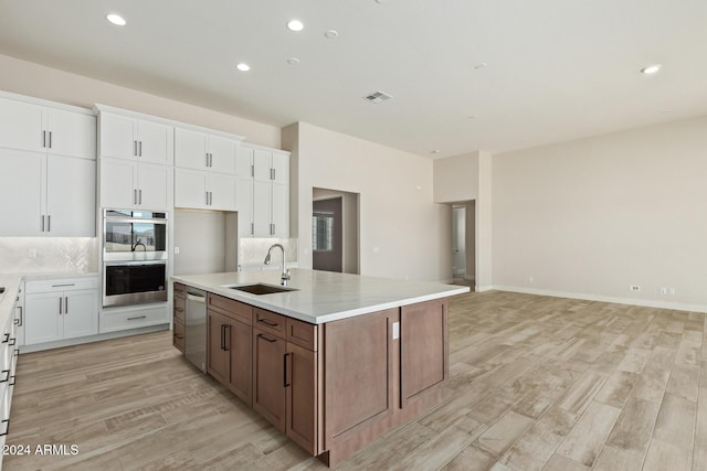 kitchen featuring a kitchen island with sink, sink, appliances with stainless steel finishes, light hardwood / wood-style floors, and white cabinetry