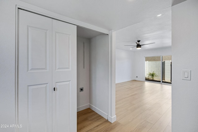 hallway with light wood-type flooring and a textured ceiling