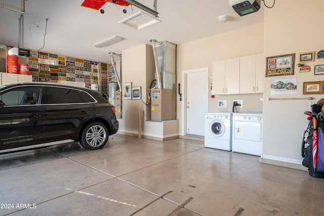 garage featuring gas water heater, a garage door opener, heating unit, and washing machine and clothes dryer