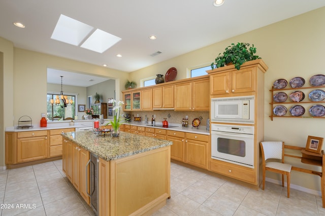 kitchen with kitchen peninsula, plenty of natural light, hanging light fixtures, and white appliances