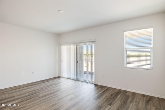 spare room featuring a wealth of natural light, baseboards, and wood finished floors