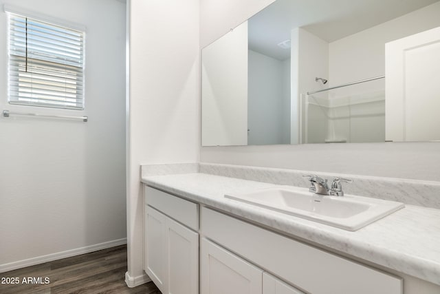 full bath with baseboards, walk in shower, wood finished floors, and vanity