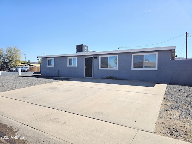 ranch-style house featuring cooling unit, fence, and stucco siding