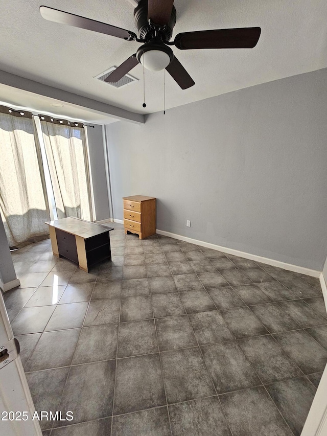 unfurnished living room with a textured ceiling, dark tile patterned floors, baseboards, and ceiling fan