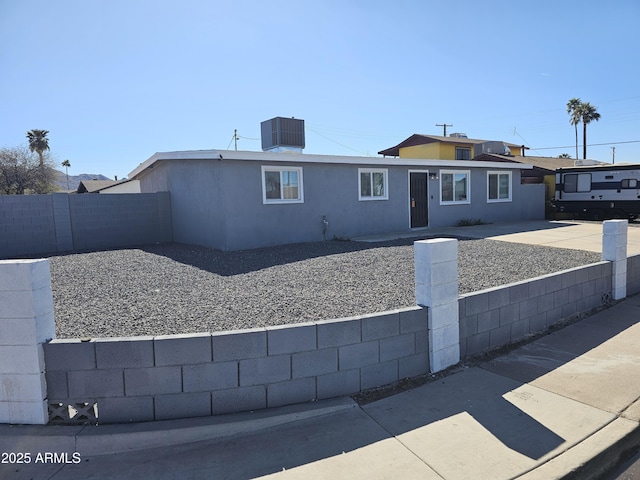 view of front of house featuring central air condition unit, stucco siding, and fence