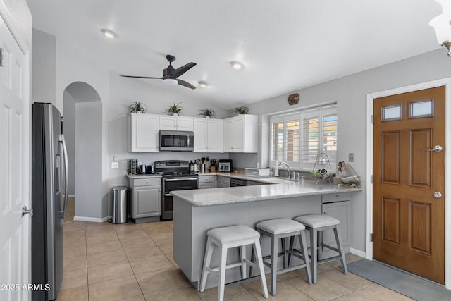1231 E Sunburst Ln, Tempe, AZ 85284 - kitchen with appliances with stainless steel finishes, a peninsula, a sink, a ceiling fan, and a kitchen breakfast bar