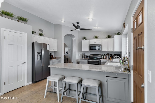 1231 E Sunburst Ln, Tempe, AZ 85284 - kitchen featuring stainless steel appliances, a peninsula, vaulted ceiling, arched walkways, and light tile patterned floors