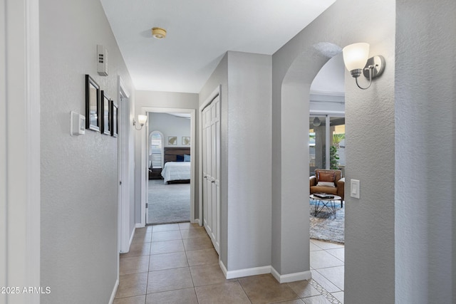 1231 E Sunburst Ln, Tempe, AZ 85284 - hallway featuring arched walkways, light tile patterned floors, a textured wall, and baseboards