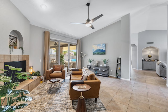 1231 E Sunburst Ln, Tempe, AZ 85284 - living area featuring arched walkways, ceiling fan, a tile fireplace, high vaulted ceiling, and light tile patterned floors