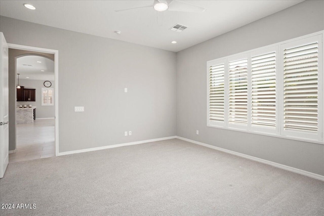 unfurnished bedroom with multiple windows, light carpet, and ceiling fan