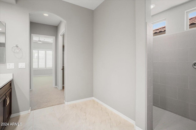 bathroom featuring tile patterned flooring, tiled shower, and vanity