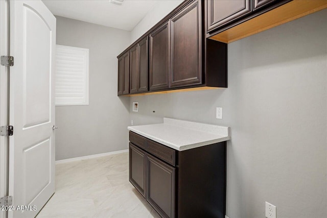 clothes washing area featuring light tile patterned floors, washer hookup, and cabinets