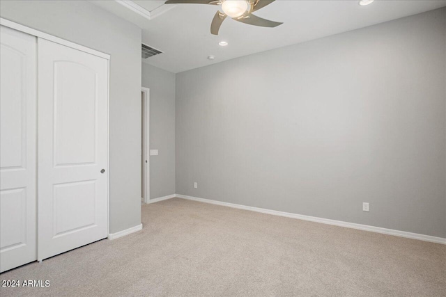 unfurnished bedroom featuring a closet, light colored carpet, and ceiling fan