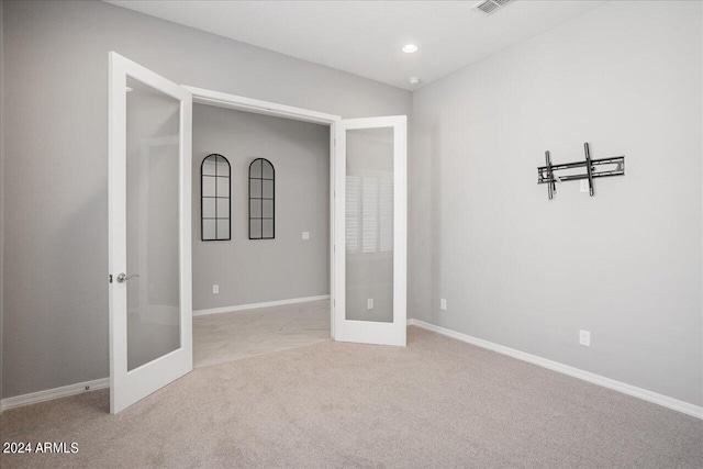 unfurnished room featuring light carpet and french doors