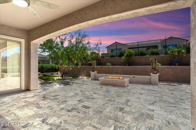 patio terrace at dusk with ceiling fan and a fire pit