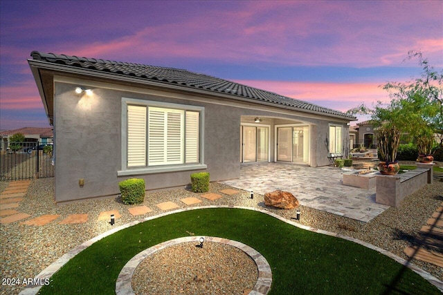 back house at dusk featuring a patio