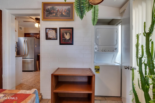 laundry area featuring stacked washing maching and dryer, ceiling fan, and light tile floors