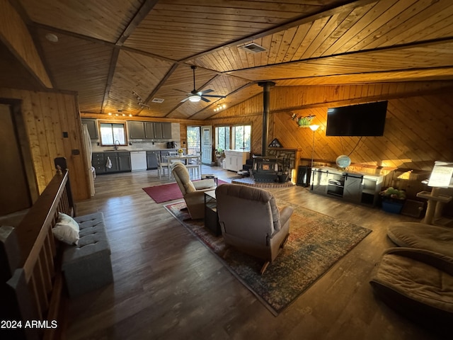 living room with vaulted ceiling, wooden ceiling, dark hardwood / wood-style floors, a wood stove, and wood walls