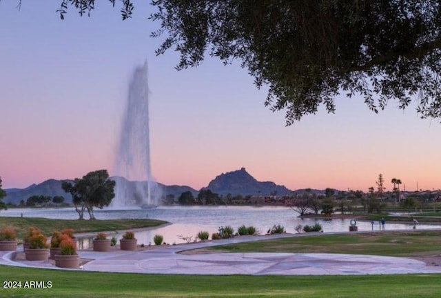 view of property's community with a water and mountain view and a lawn