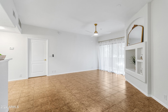 empty room featuring light tile patterned floors, built in features, and ceiling fan