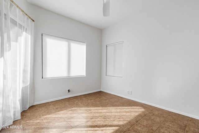 tiled spare room with ceiling fan